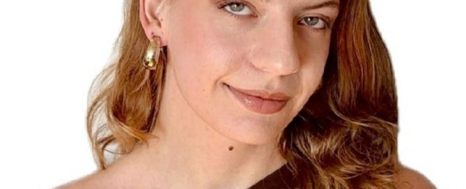 Smiling woman with wavy hair and gold earrings